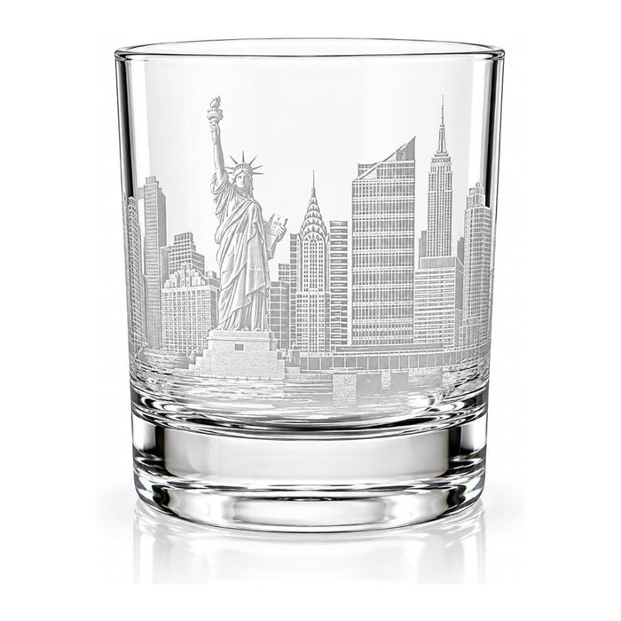 A clear glass rocks tumbler featuring an etched New York City skyline design with the Statue of Liberty and skyscrapers, shown on a white background with a soft reflection.
