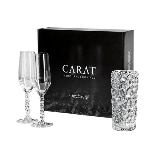 Two crystal glasses and a tall crystal vase in front of an Orrefors box on a white background